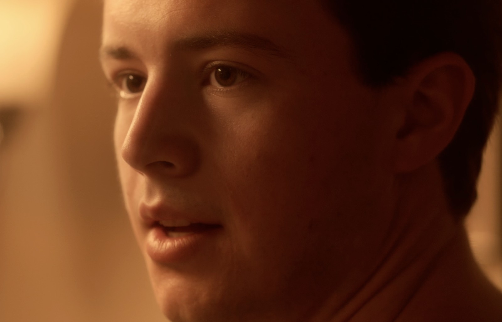 Still from Forgive Us, a warm-lit profile close-up