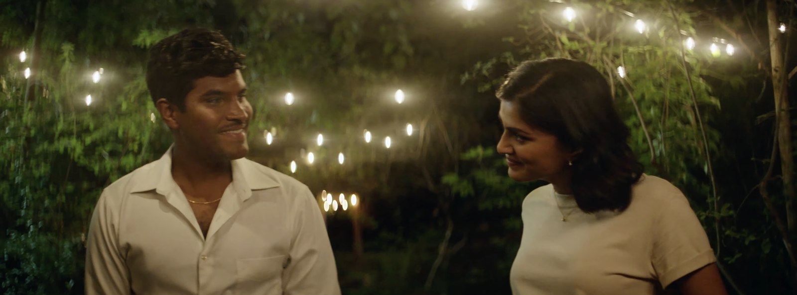 Still from Mysore Magic, a couple smiling under string lights